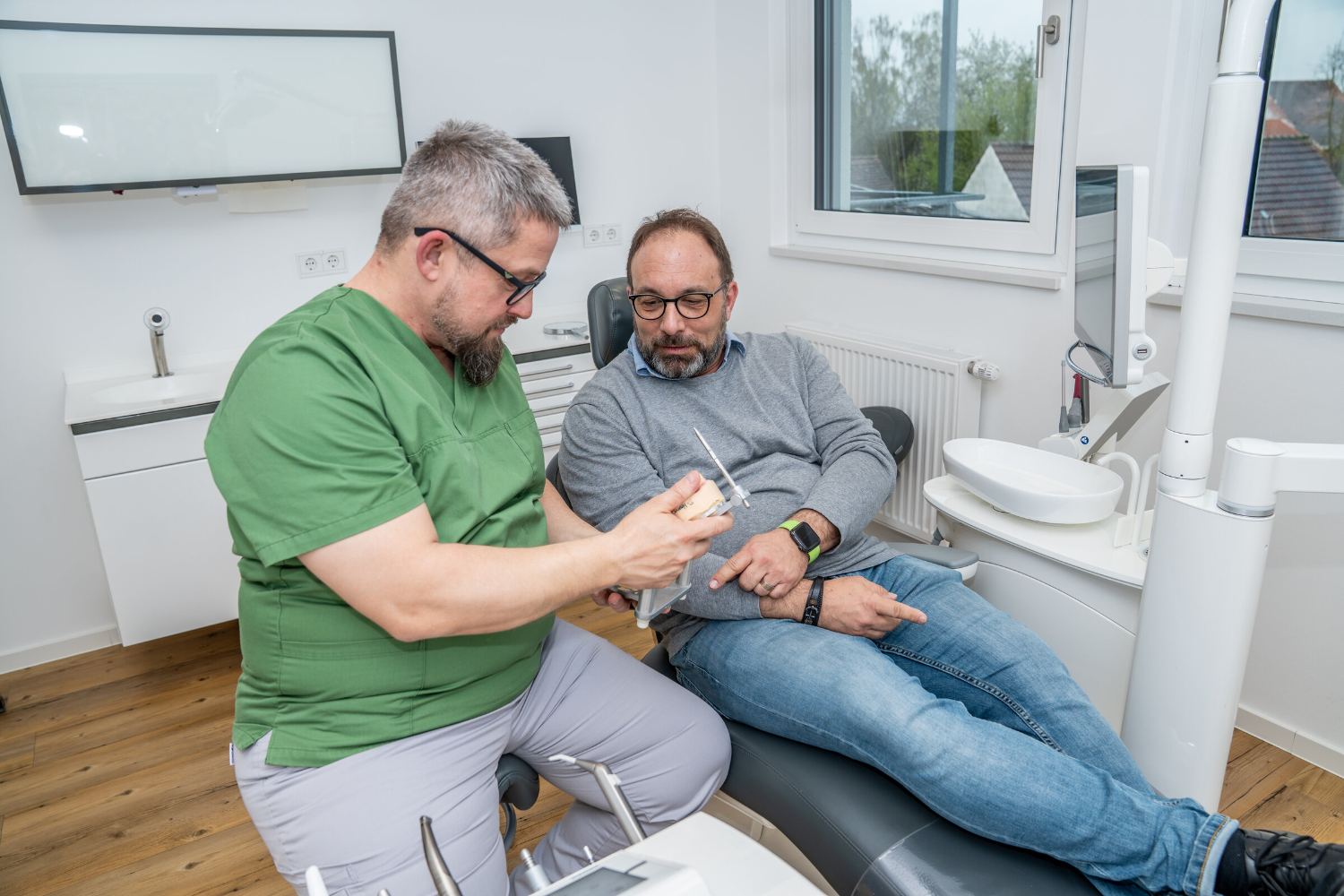Dr. Sascha Hessner erklärt einem Patienten die Behandlung am Zahnmodell